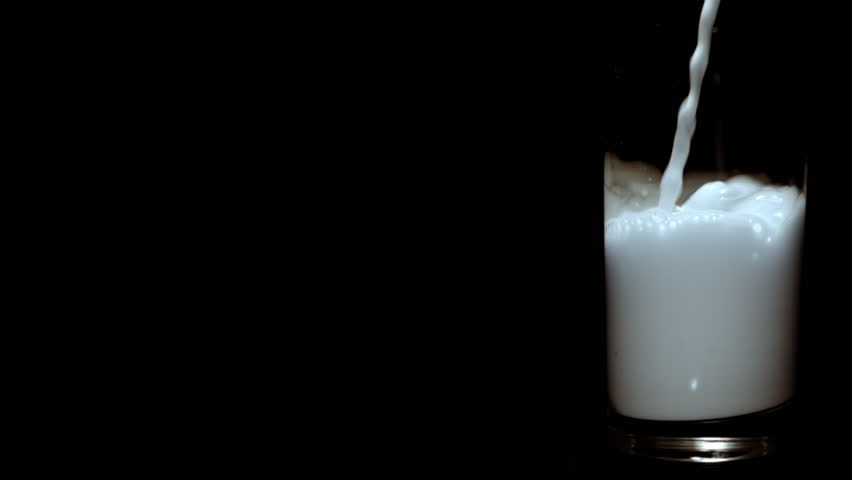Slow motion clip of milk being poured in glass on black background. (165 fps / HD-Highspeed-Camera)