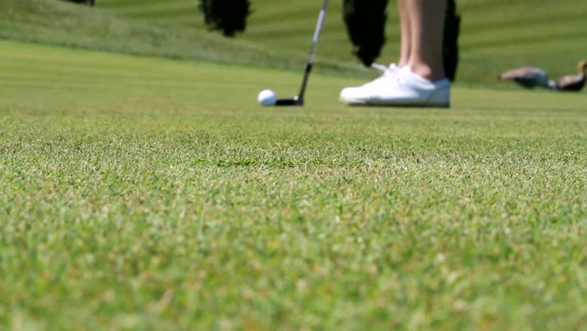 Golf player on the green sinking a putt with a curve line at finish