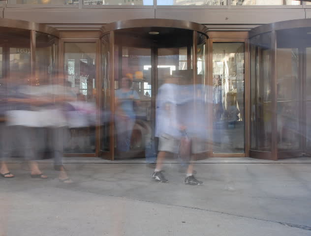 People spinning in and out revolving door time lapse