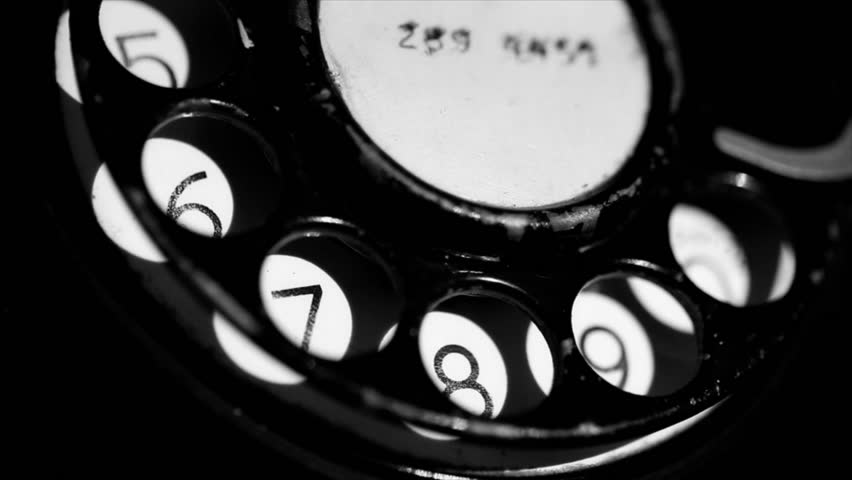 A closeup of someone dialing on an old rotary style telephone/