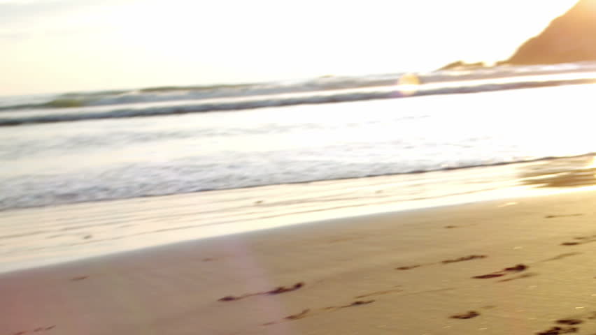 two children chase each other on the beach at sunset. lens flare. 