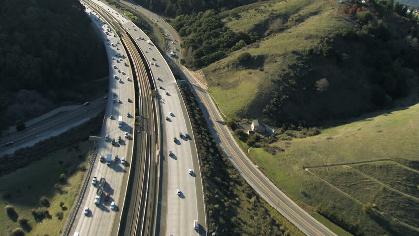Aerial view of heavy  traffic using  busy freeway in the hills outside a city