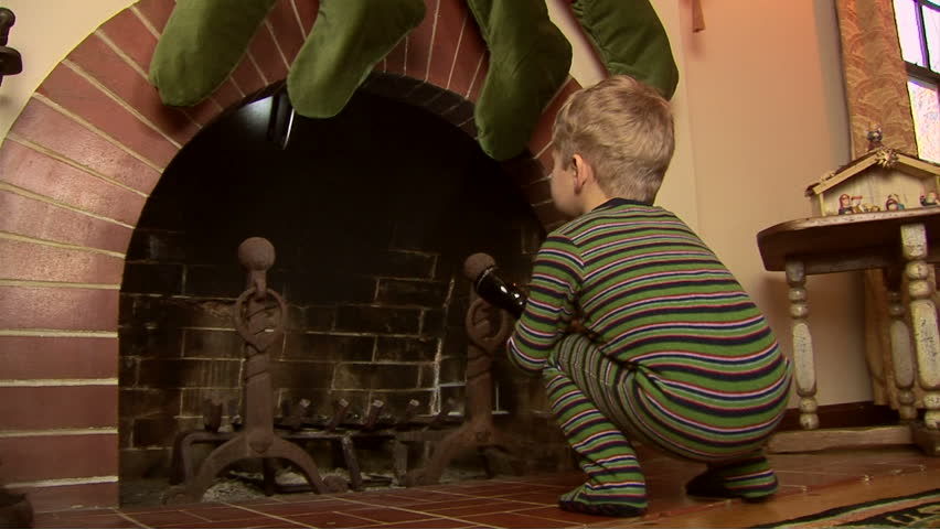 Toddler in pajamas looking for Santa in the fireplace at Christmas