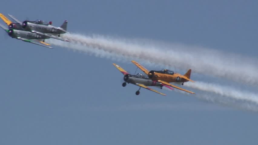 Formation of wartime T-6 Texan trainer airplanes in flight with smoke