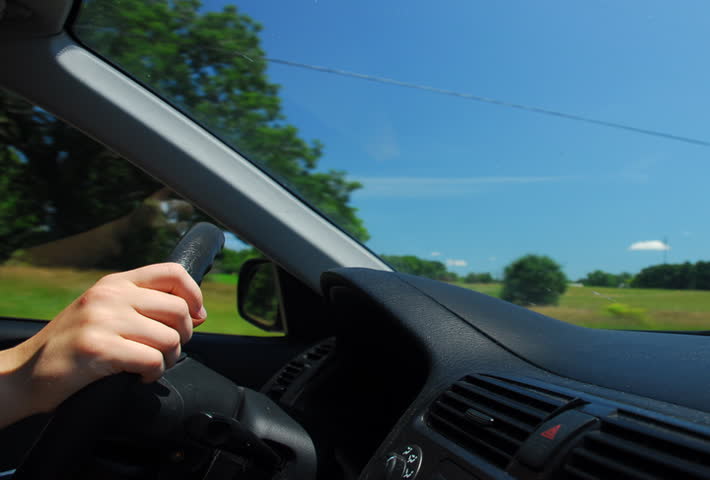 Hands on steering wheel driving through farm country time lapse