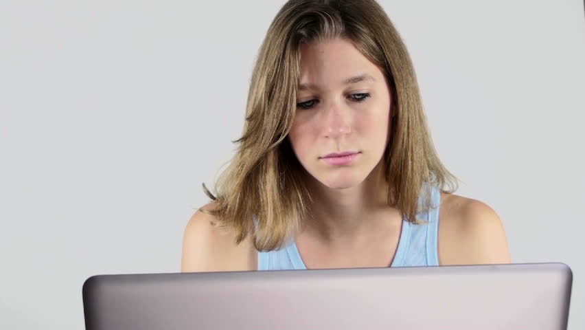 Young pretty woman sits at computer, restless, fidgety, procrastinating, trying to think of an idea, what to write. 1920x1080