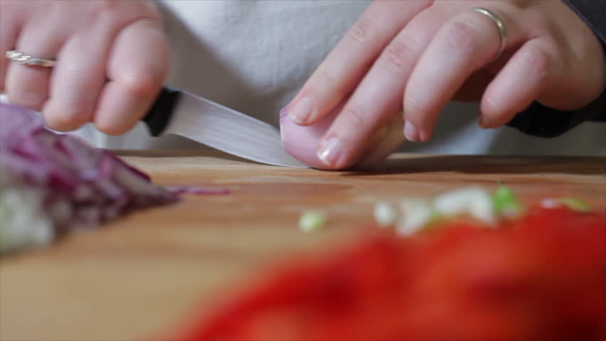 A woman chef shows how to professionally slice up a small red onion.