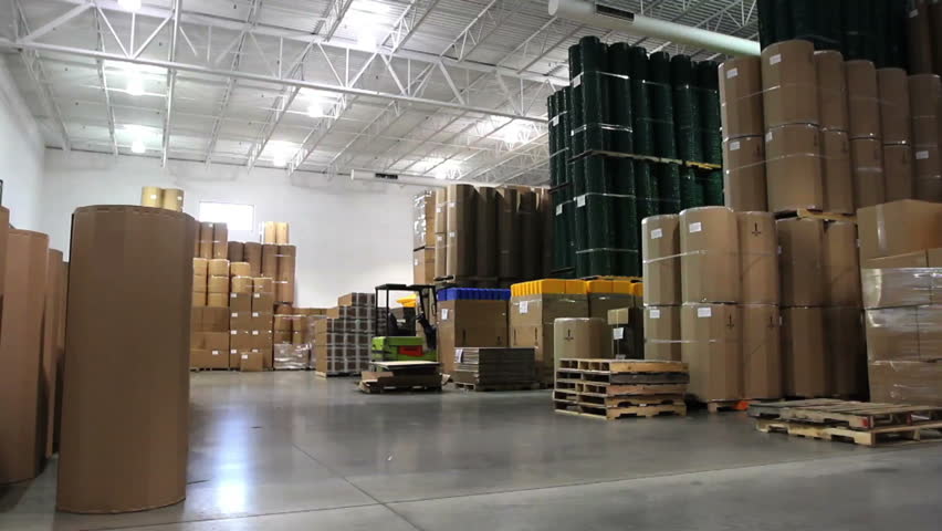 A forklift driver cruises through a large factory warehouse. 