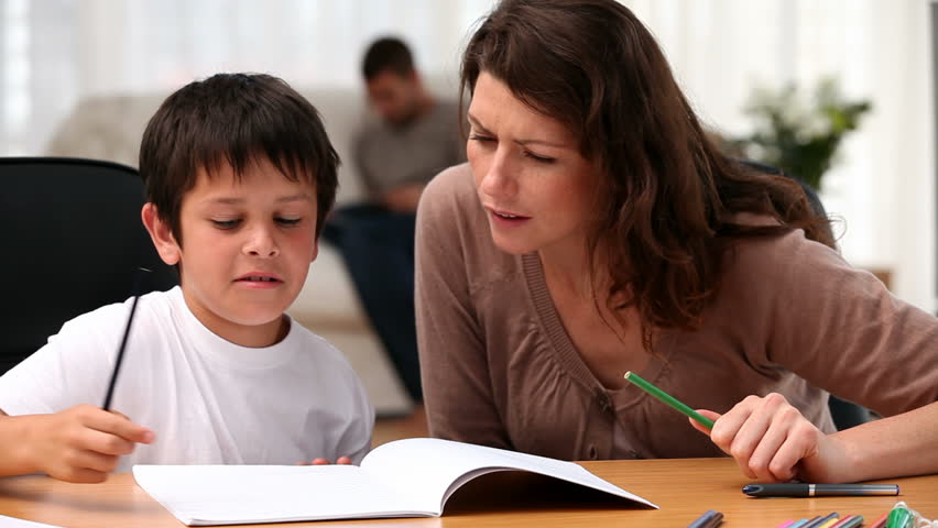 Mom helping his son to do his homework in the living room