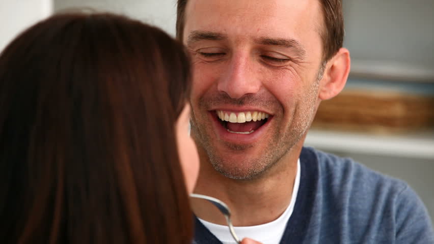 Man laughing while having dinner in the kitchen with his wife