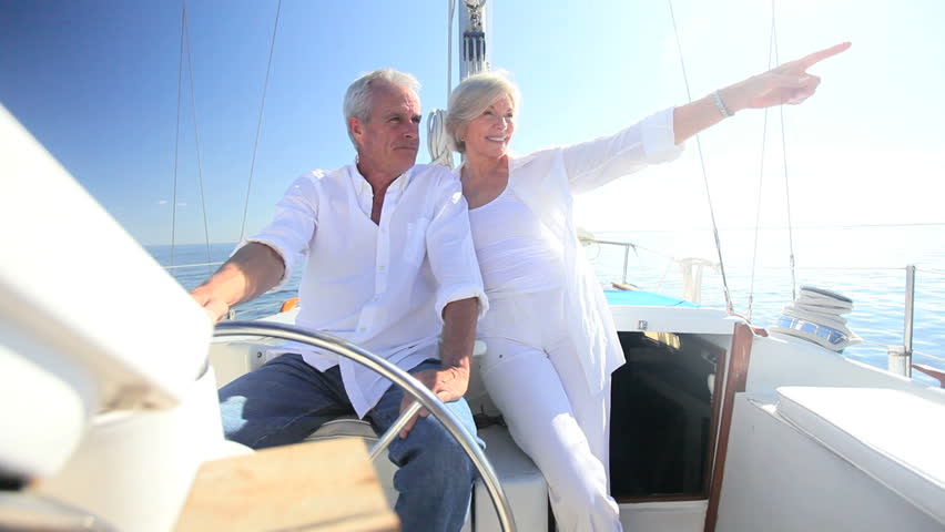Healthy retired couple steering a course aboard their luxury sailing boat