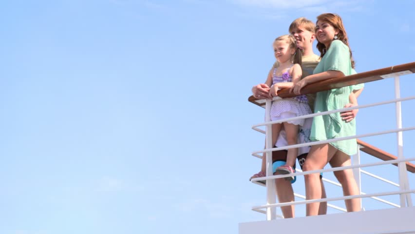 family of three people is standing at railing on deck staring into the distance
