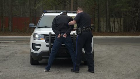 Police officer searches an arrested drunk driver who failed a DUI test during a traffic stop.