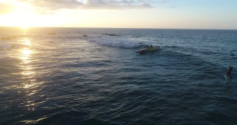 Slow motion aerial footage of a man canoe surfing a fun wave at sunset in Kailua Kona, Hawaii