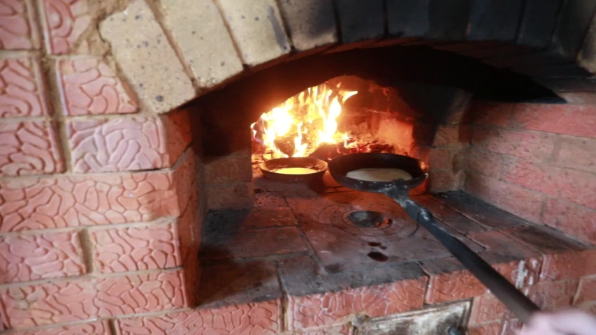 Hd00 08a Girl In National Dress Is Cooking In A Fireplace Pancakes In A