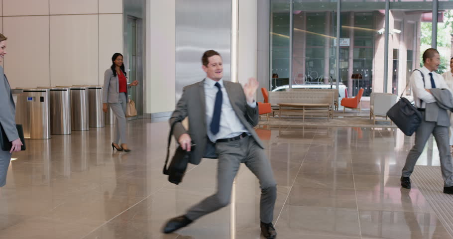 Crazy happy businessman dancing in corporate lobby wearing suit celebrating achievement