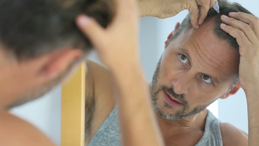 Middle Aged Man Applying Treatment For Hair Loss