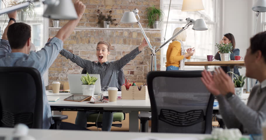 Business woman with arms raised celebrating success watching sport victory on laptop diverse people group clapping expressing excitement in office