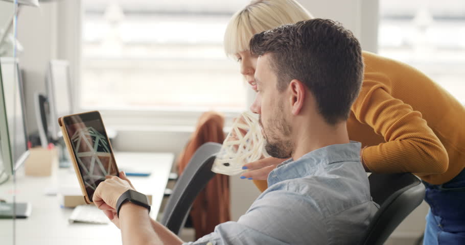 Business woman showing 3d printed object in Creative business team meeting in gender neutral start up office team leader pointing at screen discussing 3d printing technology