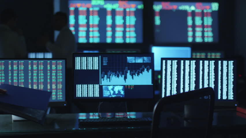 Stockbroker in white shirt is working in a dark monitoring room with display screens. Shot on RED Cinema Camera in 4K (UHD).