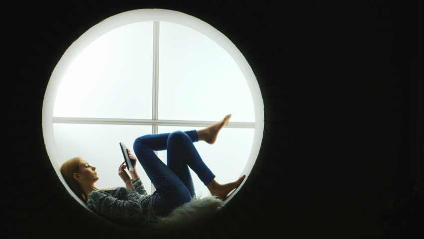 Attractive Woman Sitting At The Round Window Listening To Silhouette Of A Girl With The Tablet On Round Window Hd Stock Clip