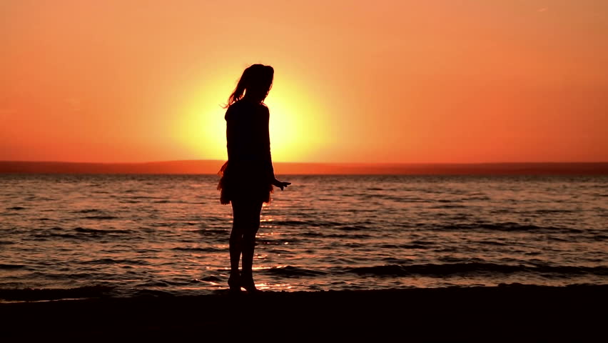 Sunset At Sea. A Girl Stands On The Beach Watching The Sunset. The ...