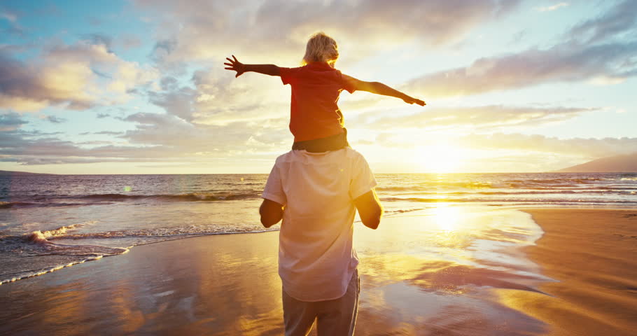 Happy father and son playing on the beach at sunset