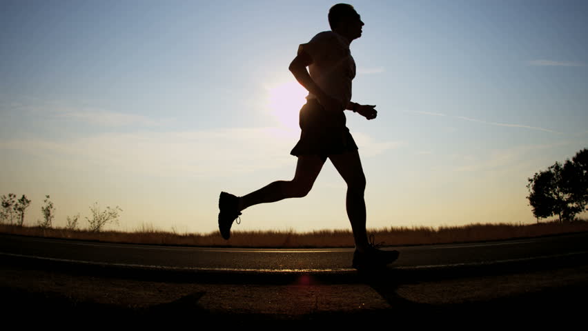 Young Man Running On Mountain Road At Sunset Above The Clouds. Slow ...