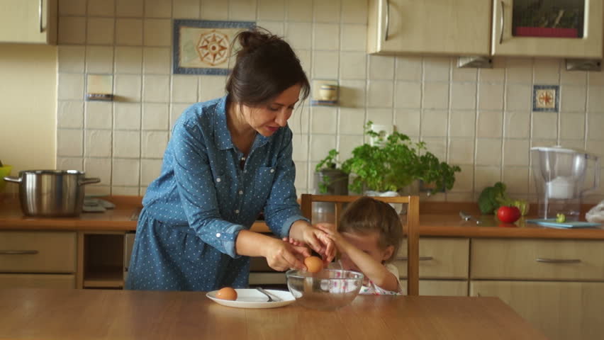 Baby Helps Mom In The Kitchen The Girls Break Eggs Into A Glass Bowl Baby Helps Mom In The Kitchen The Girls Break Eggs Into A Glass Bowl