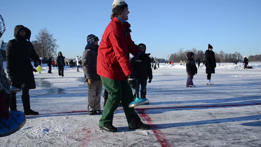 people play winter game eisstock curling and slide skating kit frozen ice on circa January in Trakai.