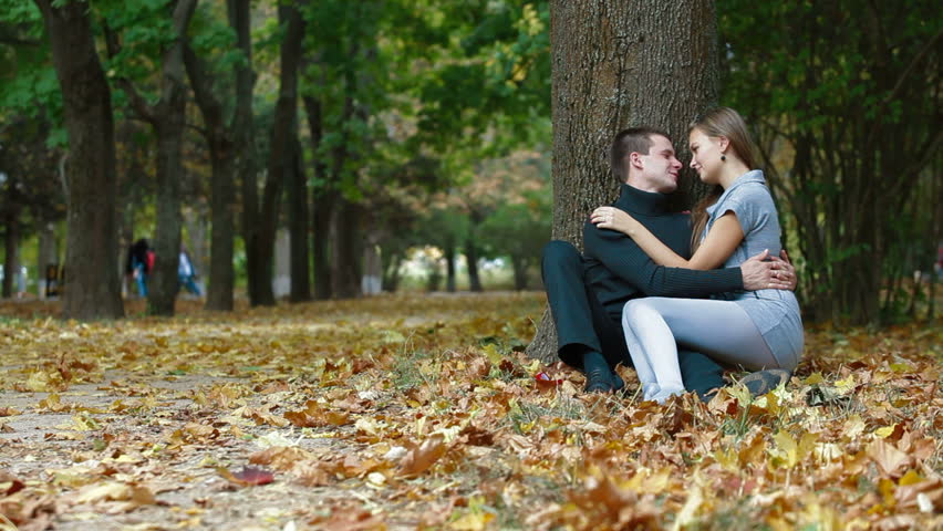 Romantic Teenage Couple Sitting Under A Tree On Fallen Leaves In Autumn ...