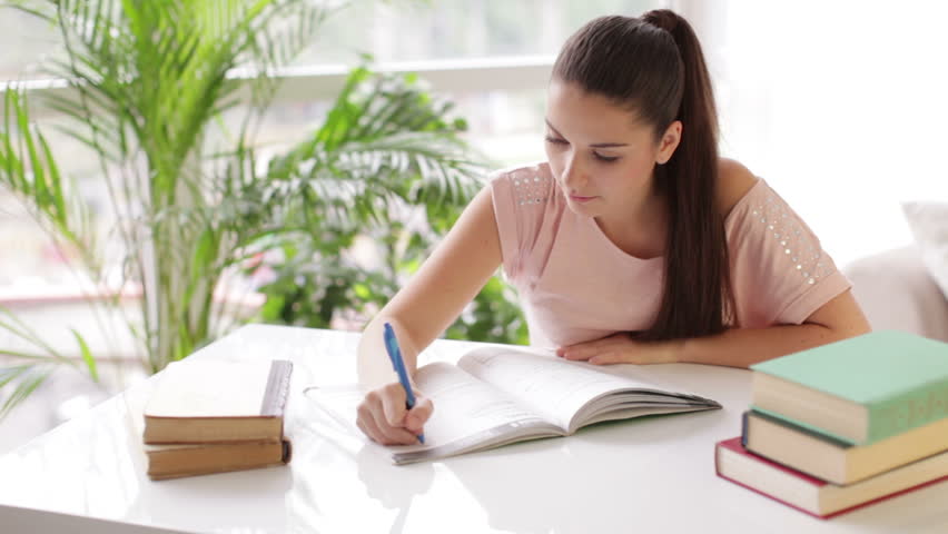 Attractive Girl Studying At Table With Books And Looking At Camera With ...