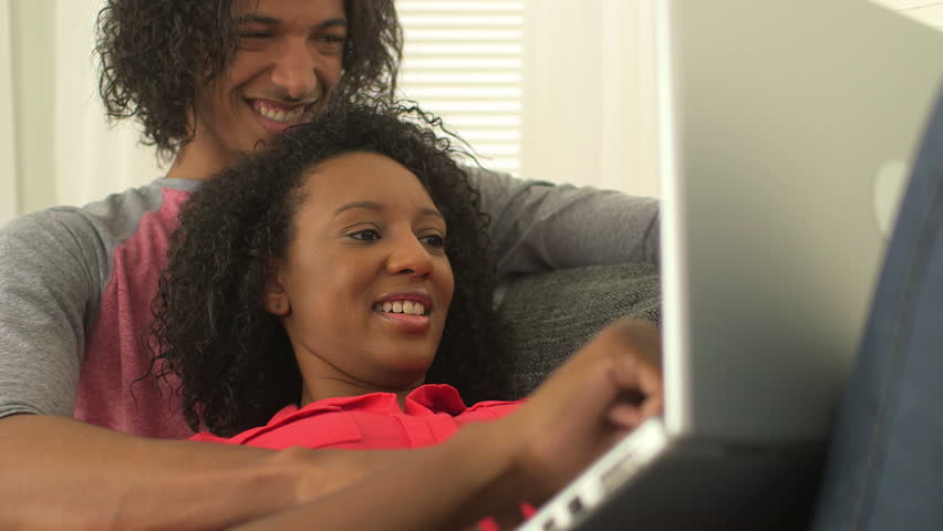 Couple Sitting On Sofa Disagreeing About What To Watch On Tv