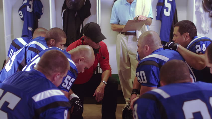 Football Players Listen To Their Coach Give A Speech In The Locker Room
