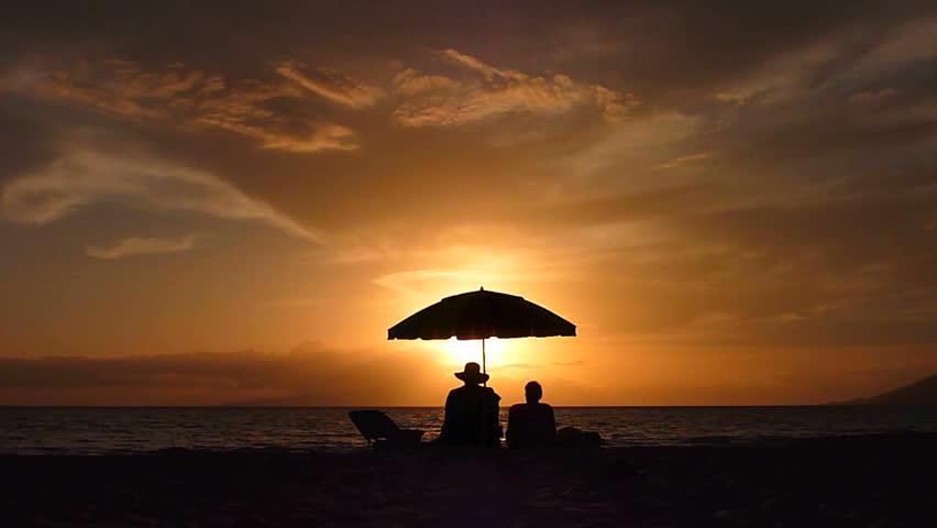 Man And Woman Couple Sit Under Umbrella Together Along Sandy Beach ...