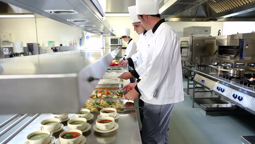Busy Restaurant Kitchen waitress collects her order from the chef in a busy hotel or Busy Restaurant Kitchen waitress collects her order from the chef in a busy hotel or