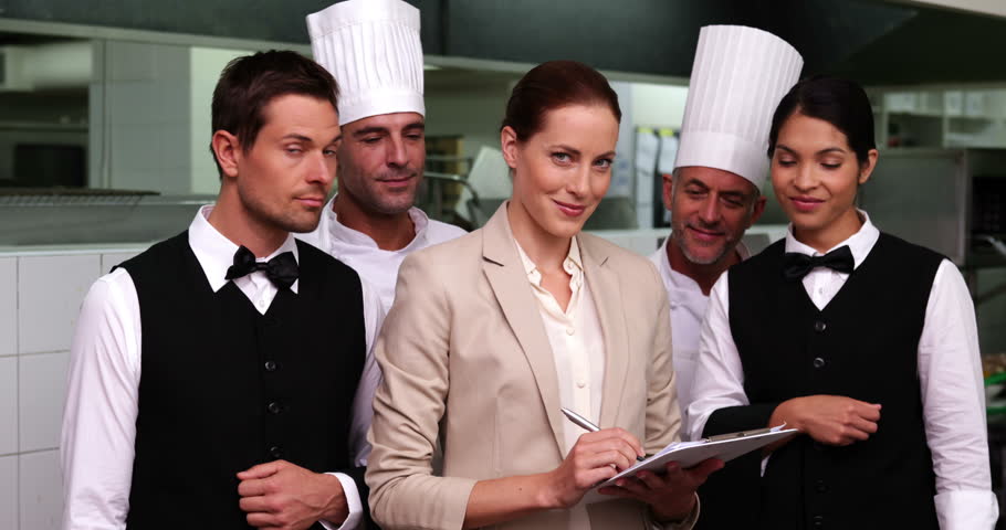 Restaurant Kitchen Manager serious restaurant staff with manager looking at camera in a Restaurant Kitchen Manager serious restaurant staff with manager looking at camera in a