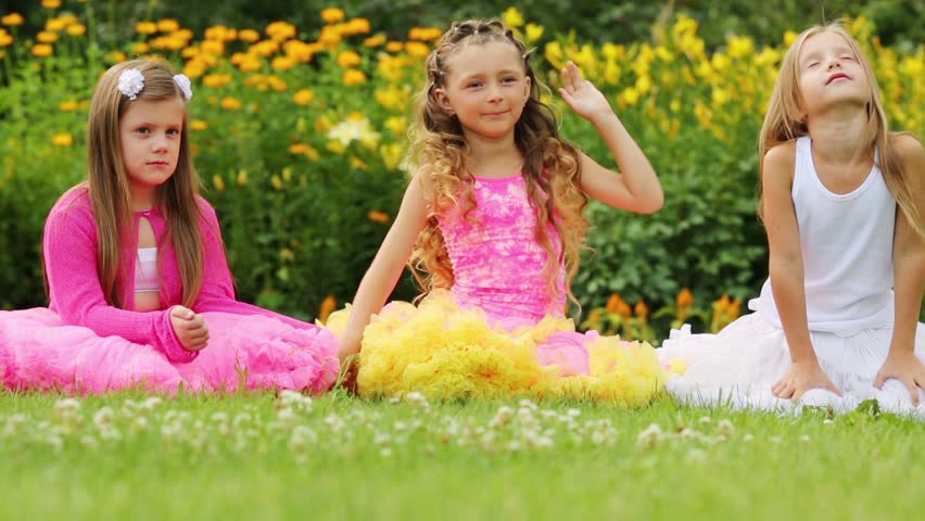 little-girl-in-pink-lush-skirt-walks-at-stone-path-among-bushes-in