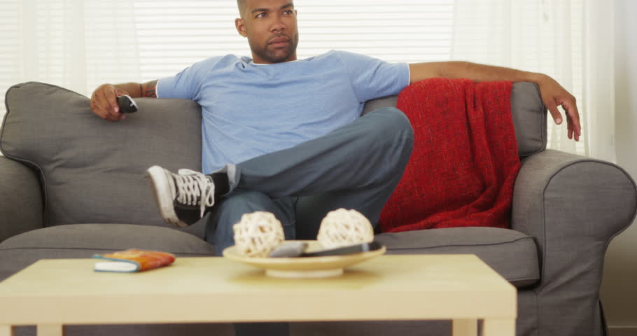 African Man Sitting On Couch Watching Tv